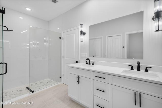 full bath with a shower stall, visible vents, double vanity, and a sink