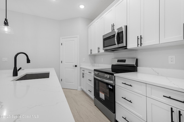 kitchen with recessed lighting, decorative light fixtures, a sink, stainless steel appliances, and white cabinets