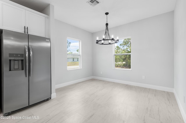 unfurnished dining area featuring a chandelier, baseboards, and visible vents