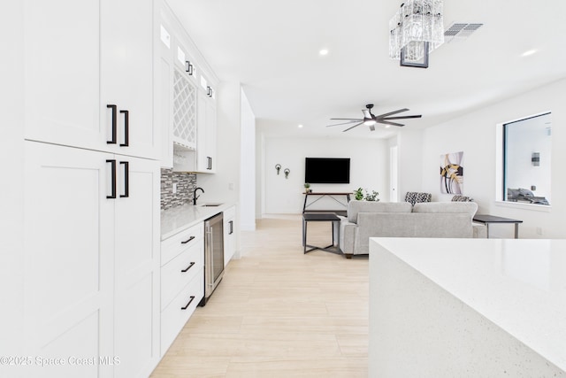 kitchen with a sink, light countertops, backsplash, white cabinetry, and recessed lighting