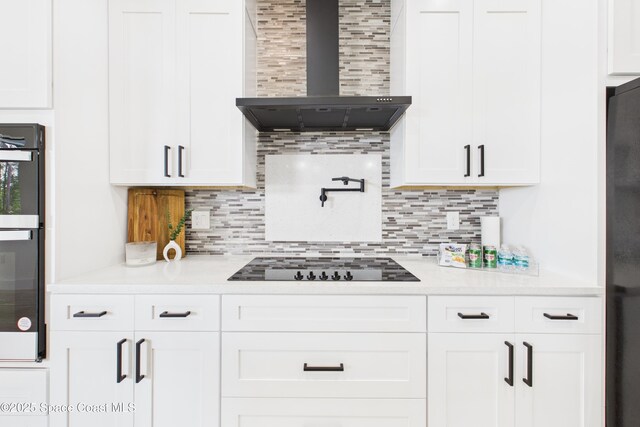 kitchen with wall chimney exhaust hood, decorative backsplash, white cabinetry, and black appliances