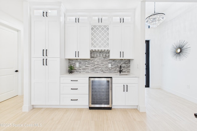 bar featuring wine cooler, wet bar, a sink, baseboards, and decorative backsplash