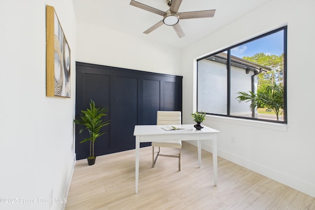 home office with light wood finished floors, a ceiling fan, and baseboards