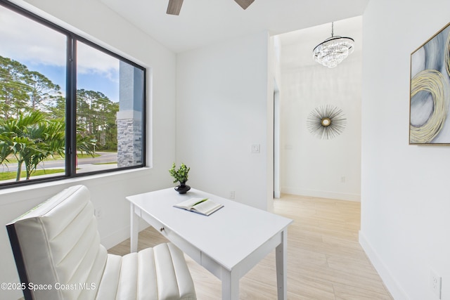 home office with ceiling fan with notable chandelier, baseboards, and a wealth of natural light