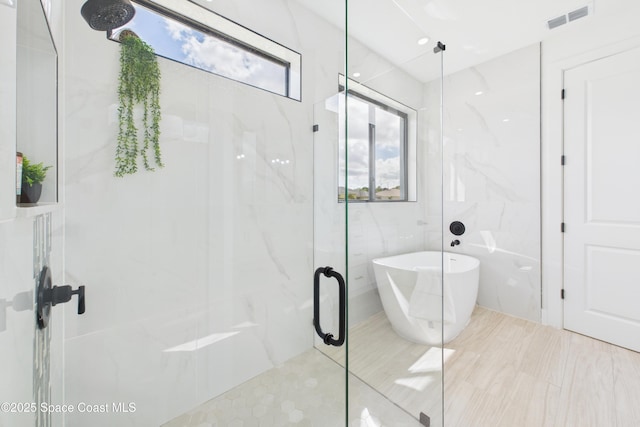 full bath with a marble finish shower, a soaking tub, and visible vents