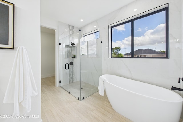 bathroom with a soaking tub, a marble finish shower, and recessed lighting