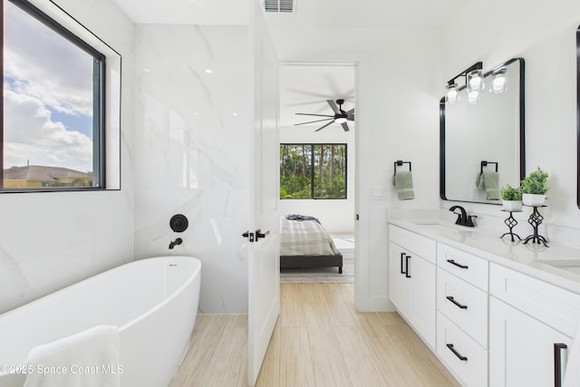 bathroom with a ceiling fan, a sink, a soaking tub, double vanity, and ensuite bath