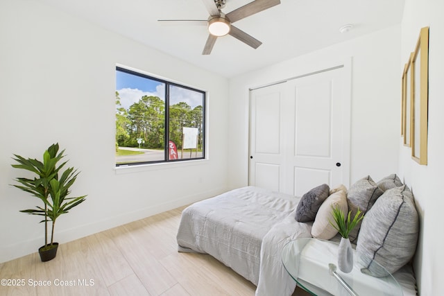 bedroom featuring light wood-style flooring, a closet, baseboards, and ceiling fan