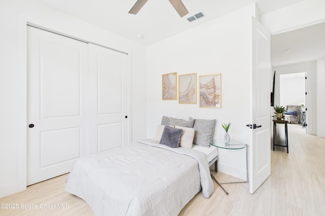 bedroom with a ceiling fan, light wood-style floors, visible vents, and a closet