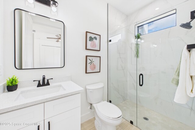 bathroom featuring a ceiling fan, toilet, vanity, and a marble finish shower