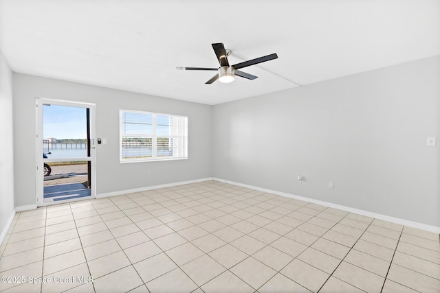 unfurnished room featuring baseboards, a ceiling fan, and a water view