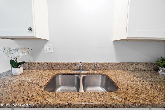 details with a sink, white cabinetry, and light stone countertops