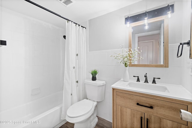 bathroom with shower / bathtub combination with curtain, vanity, visible vents, toilet, and tile walls
