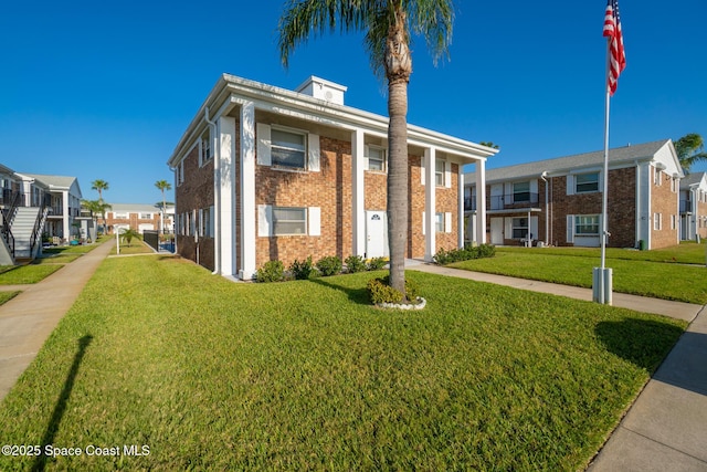 view of front of house featuring a front yard, brick siding, and a residential view