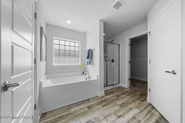 1830 San Filippo Dr SE, Palm Bay, FL 32909 - full bath with visible vents, a bath, a textured ceiling, a shower stall, and wood finished floors