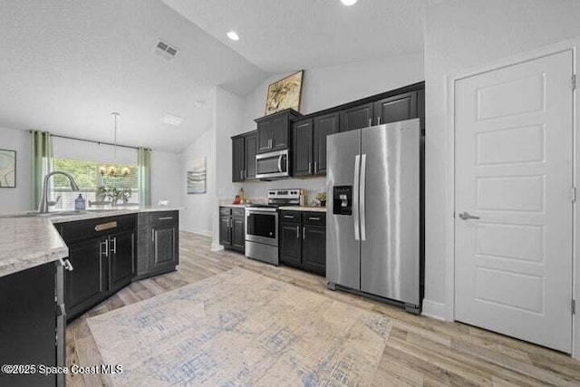 1830 San Filippo Dr SE, Palm Bay, FL 32909 - kitchen featuring a notable chandelier, vaulted ceiling, dark cabinetry, stainless steel appliances, and a sink