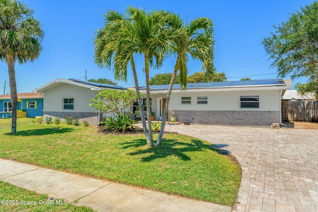 170 Maple Dr, Satellite Beach, FL 32937 - ranch-style home featuring solar panels, brick siding, fence, and a front lawn