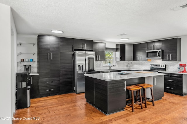170 Maple Dr, Satellite Beach, FL 32937 - kitchen featuring dark cabinetry, stainless steel appliances, visible vents, and decorative backsplash