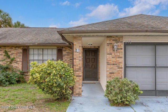618 Americana Blvd NE, Palm Bay, FL 32907 - property entrance with roof with shingles, brick siding, and a garage