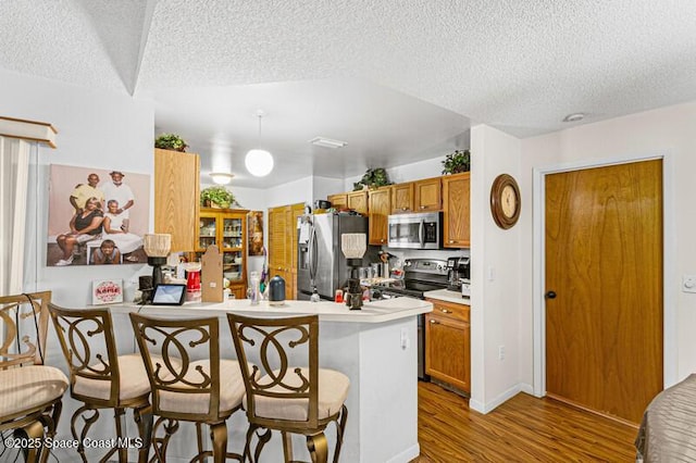 618 Americana Blvd NE, Palm Bay, FL 32907 - kitchen featuring stainless steel appliances, a kitchen breakfast bar, wood finished floors, and a textured ceiling