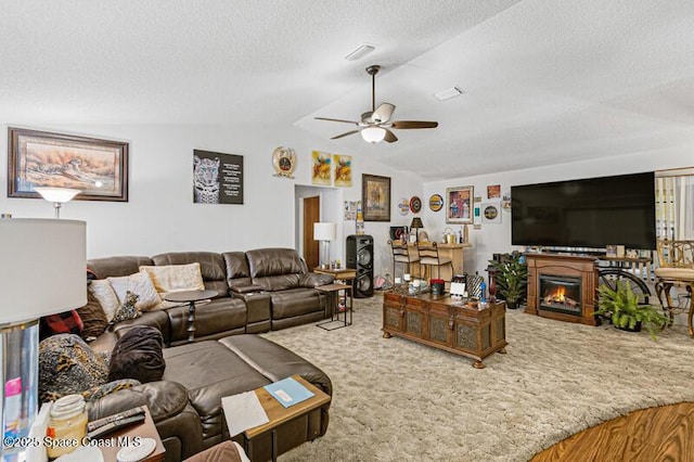 618 Americana Blvd NE, Palm Bay, FL 32907 - living area featuring a glass covered fireplace, carpet, visible vents, lofted ceiling, and a ceiling fan