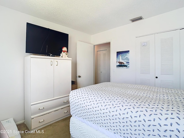 bedroom featuring visible vents, a textured ceiling, carpet flooring, and a closet