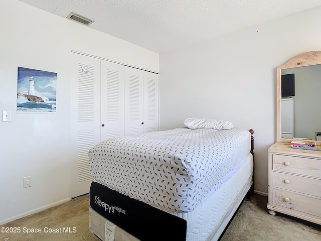 bedroom with a closet, visible vents, light colored carpet, and baseboards