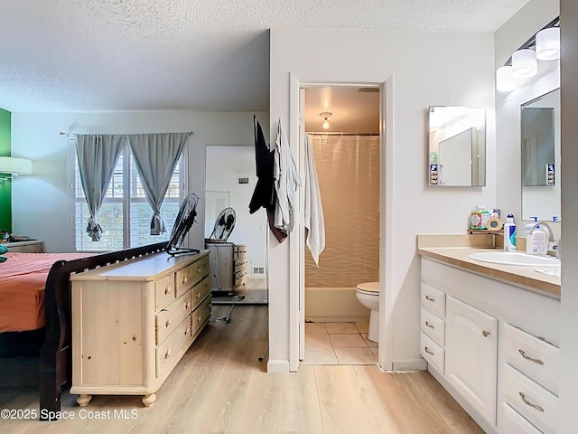 bathroom with a shower with shower curtain, vanity, a textured ceiling, toilet, and wood finished floors