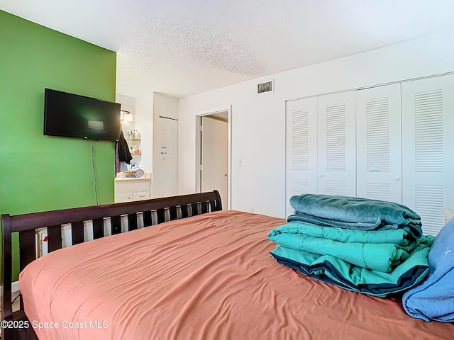 bedroom featuring visible vents, a closet, and a textured ceiling