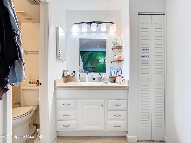 bathroom featuring vanity, a closet, and toilet