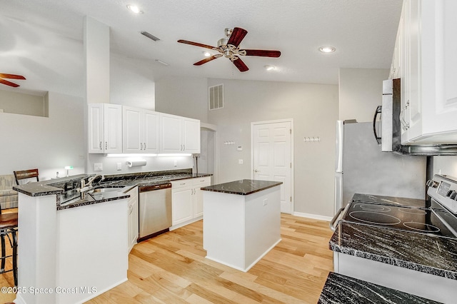 kitchen featuring visible vents, a center island, ceiling fan, a peninsula, and stainless steel appliances