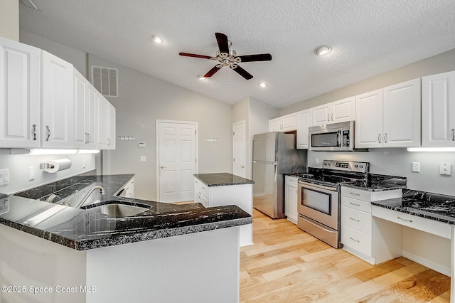 kitchen with visible vents, a sink, lofted ceiling, stainless steel appliances, and light wood finished floors