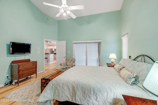 bedroom featuring baseboards, ceiling fan, freestanding refrigerator, wood finished floors, and high vaulted ceiling