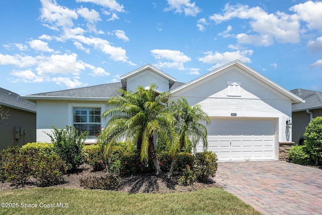 ranch-style home with an attached garage, decorative driveway, and stucco siding