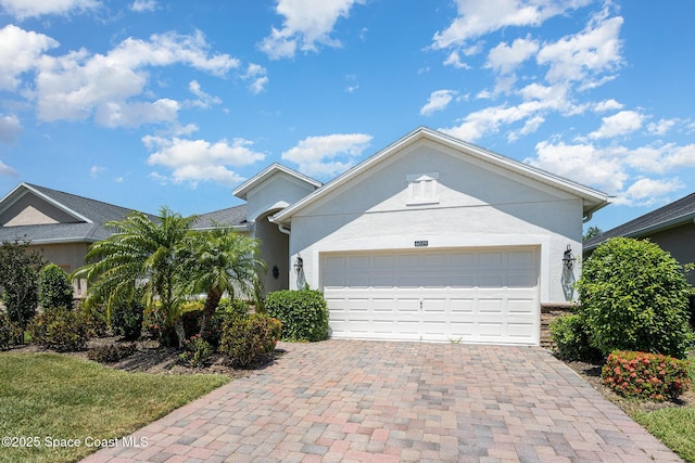 ranch-style house with an attached garage, decorative driveway, and stucco siding