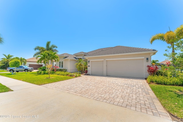 ranch-style home with a garage, decorative driveway, a front lawn, and stucco siding