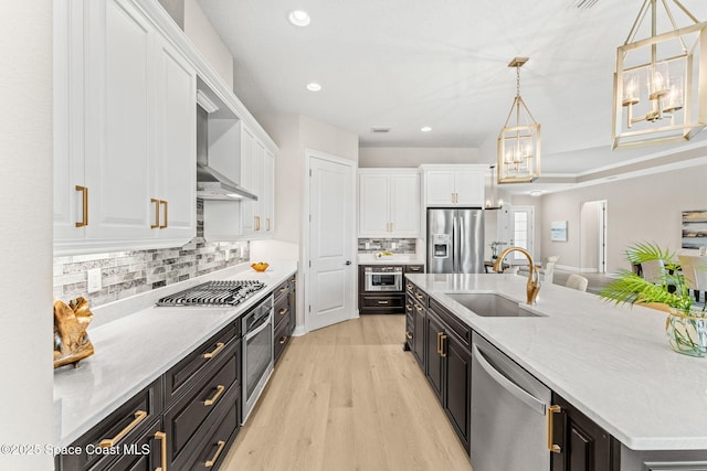 kitchen with an inviting chandelier, white cabinetry, dark cabinets, a sink, and stainless steel appliances