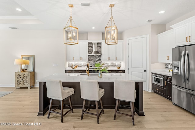 kitchen featuring wall chimney range hood, visible vents, tasteful backsplash, stainless steel fridge with ice dispenser, and white cabinetry