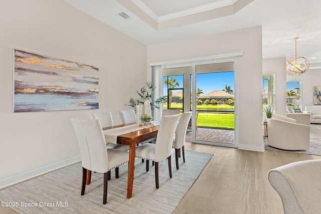 dining room featuring crown molding, a notable chandelier, wood finished floors, a tray ceiling, and visible vents