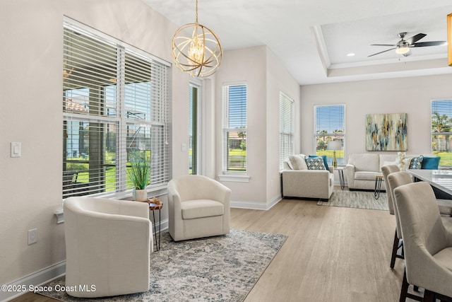 living room with wood finished floors, baseboards, recessed lighting, a tray ceiling, and ceiling fan with notable chandelier