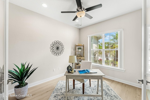 office space with baseboards, a ceiling fan, light wood-style flooring, and visible vents