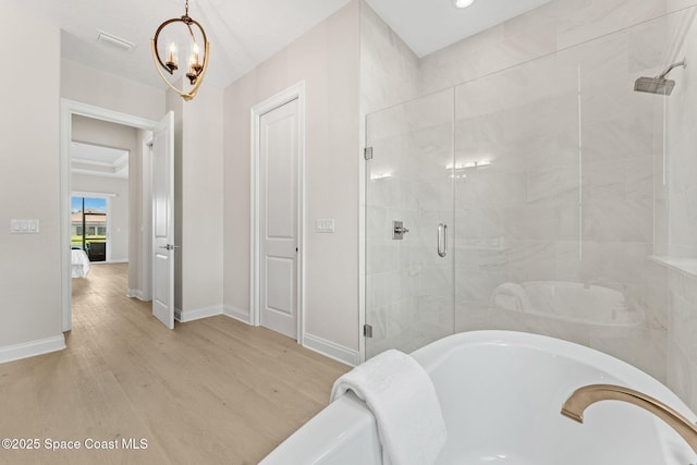 bathroom featuring visible vents, a freestanding bath, a shower stall, wood finished floors, and baseboards