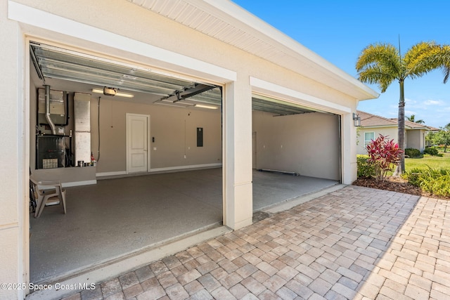 garage with heating unit, a garage door opener, electric panel, and driveway
