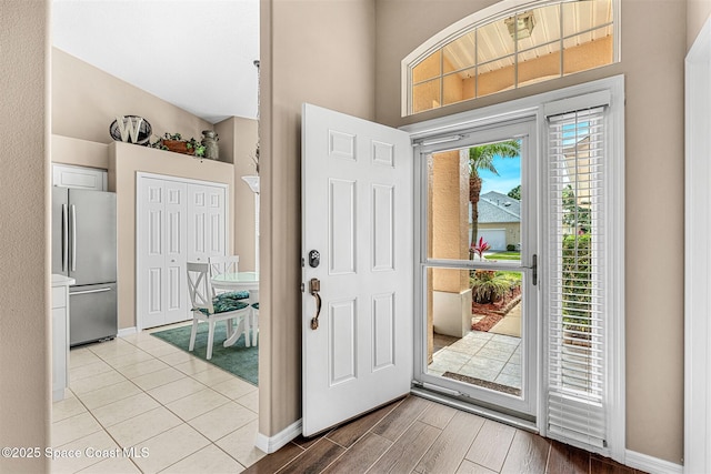 foyer entrance featuring baseboards, wood finished floors, and a towering ceiling