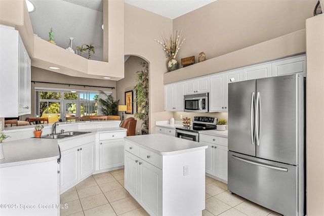 kitchen featuring a sink, light tile patterned floors, light countertops, a towering ceiling, and appliances with stainless steel finishes