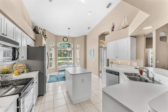 kitchen with stainless steel appliances, light countertops, a kitchen island, a sink, and visible vents