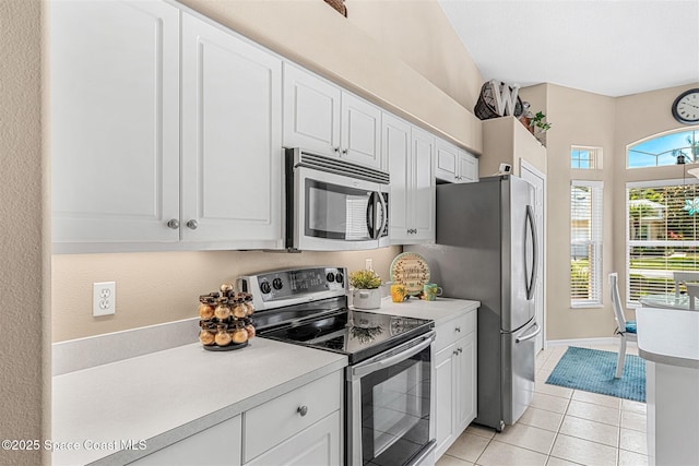 kitchen featuring light tile patterned floors, appliances with stainless steel finishes, light countertops, white cabinets, and baseboards