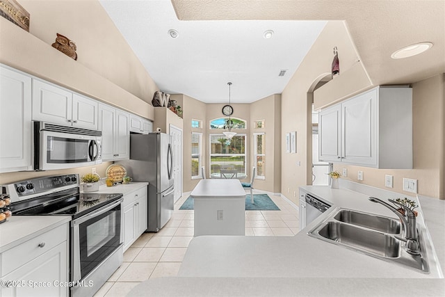 kitchen featuring a sink, light tile patterned flooring, a kitchen island, light countertops, and appliances with stainless steel finishes