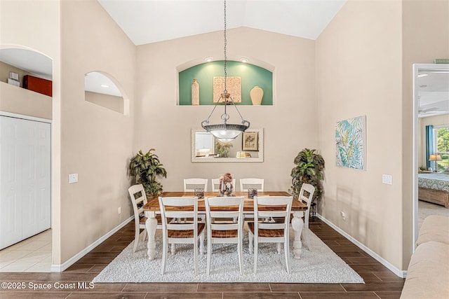 dining room featuring baseboards, high vaulted ceiling, and wood tiled floor