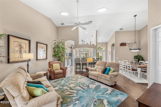 living area with high vaulted ceiling, arched walkways, ceiling fan, and wood finished floors